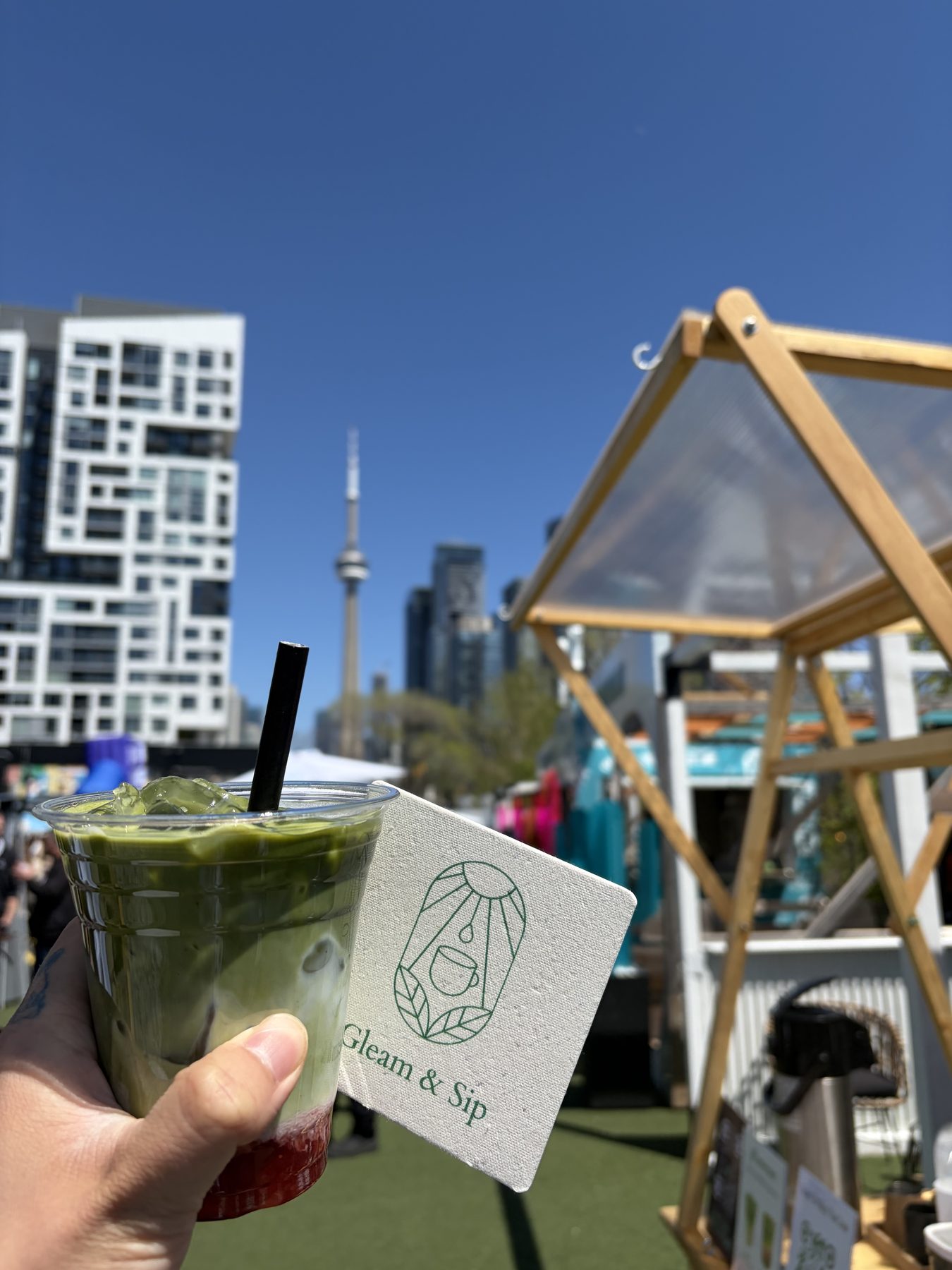A hand holding a complete layered matcha drink at the Native Touch activation